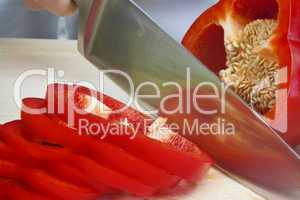Chef In Kitchen Slicing A Red Pepper With Sharp Knife