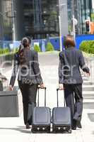 Two Women Business Travellers Walking With Rolling Suitcases