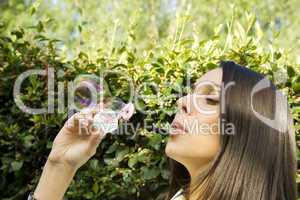 Young woman blowing bubbles in green park