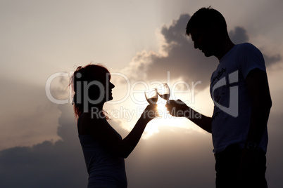 Silhouette of couple clinking glasses of wine