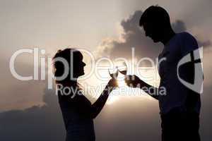 Silhouette of couple clinking glasses of wine