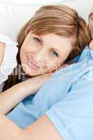 Close-up of a smiling woman hugging her boyfriend lying on a sof