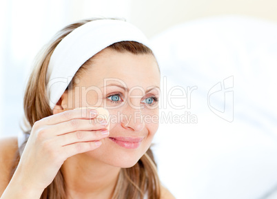 Cheerful woman putting make-up at home