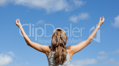 Young woman meditating against a blue sky