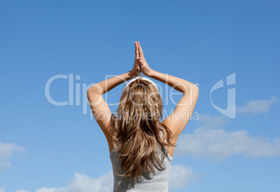 Blond woman meditating against a blue sky