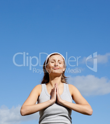 Radiant woman meditating against a blue sky