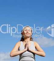Radiant woman meditating against a blue sky