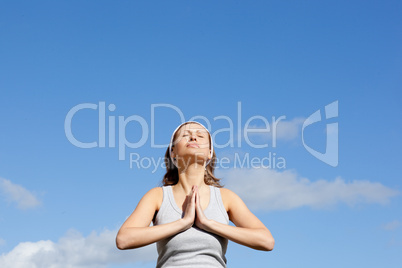 Relaxed woman meditating against a blue sky