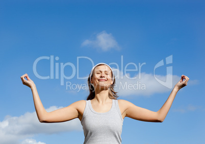 Smiling woman meditating against a blue sky
