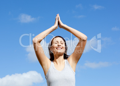 Cheerful woman doing yoga against blue sky