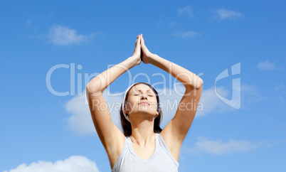 Relaxed woman doing yoga against blue sky