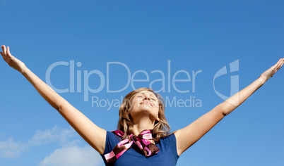 Smiling  blond woman punching tha air against blue sky