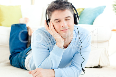 Handsome young man listening music lying on the floor