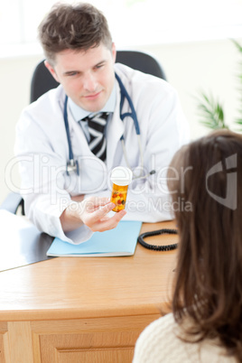 Young male doctor giving pills to a paient