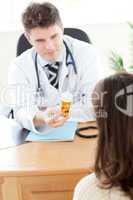Young male doctor giving pills to a paient