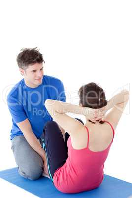 Brunette woman exercising assisted by a personal coach