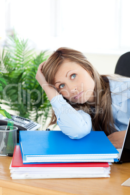 Unhappy young businesswoman sitting at her desk