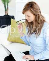 Attractive woman using a laptop sitting on a sofa