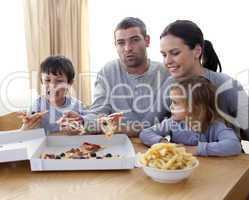 Cheerful young family eating a pizza in the living-room