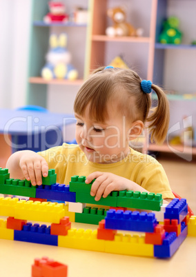 Little girl play with building bricks in preschool