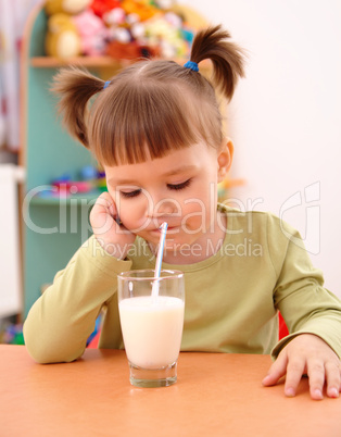 Gloomy little girl drinks milk