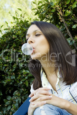 Girl in front of a green leaf blowing bubble