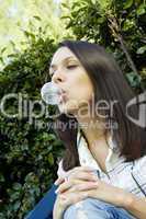 Girl in front of a green leaf blowing bubble
