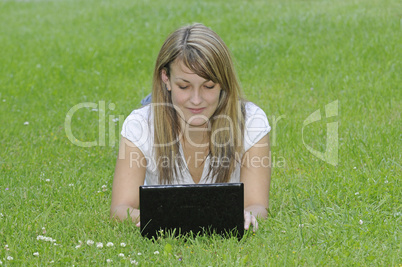 Junge Frau mit Netbook auf Wiese