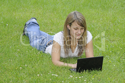 Junge Frau mit Netbook auf Wiese