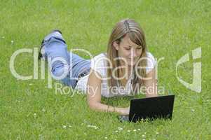 Junge Frau mit Netbook auf Wiese