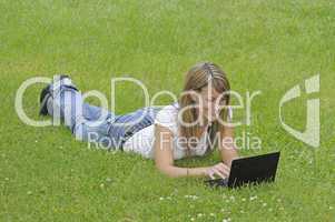 Junge Frau mit Netbook auf Wiese