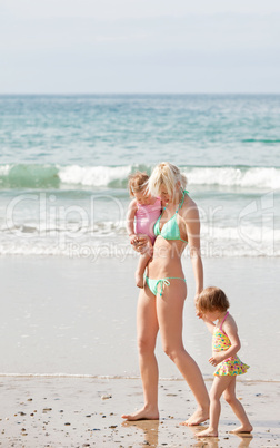 A young mother walking at the beach with her children