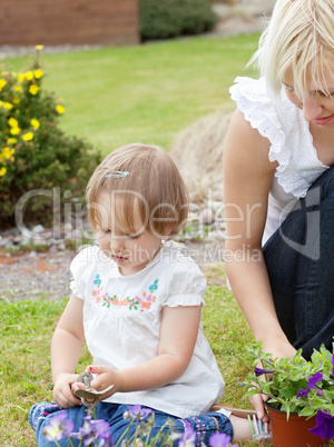Sweet girl with garden tool sitting besides her mother