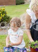 Sweet girl with garden tool sitting besides her mother