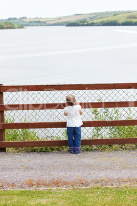 Little child standing in front of a fence