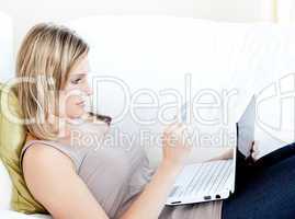 Attractive woman lying on a sofa with a laptop
