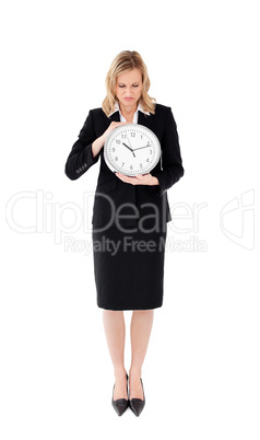 Glum businesswoman holding a clock