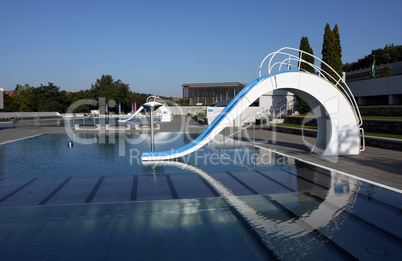 dispeopled bath pool with white slide