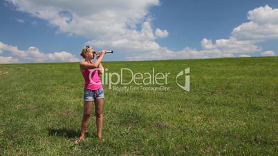 Young woman in a field look into spyglass