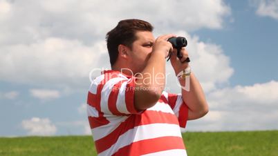 Man in a field look into binoculars