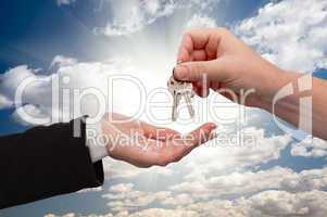 Male Handing Keys to Female Over Clouds and Rays