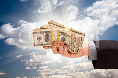 Male Hand Holding Stack of Cash Over Clouds and Sky