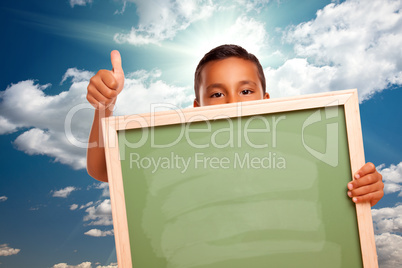 Proud Hispanic Boy Holding Blank Chalkboard Over Sky