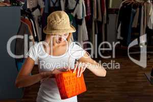 junge Frau durchsucht ihre Handtasche in einer Boutique