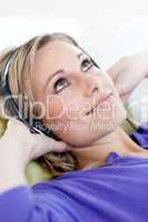 Attractive blond woman listening music lying on a sofa