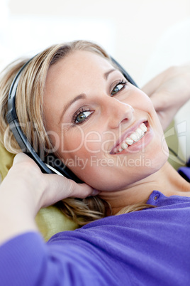 Charming woman lying down on sofa listening music