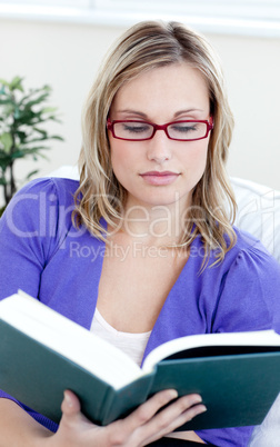 Young woman with glasses reading a book
