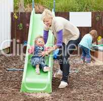 Little girl and her beautiful mother having fun with a chute