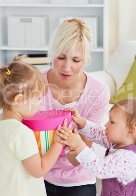 Smiling woman offering a gift to her girl in the living-room
