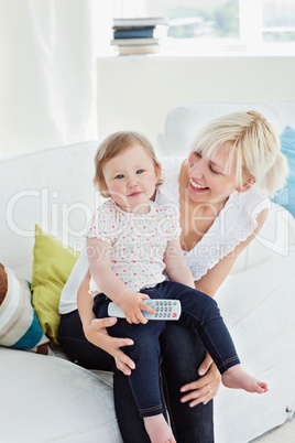Young woman using a remote with her girl in the living-room